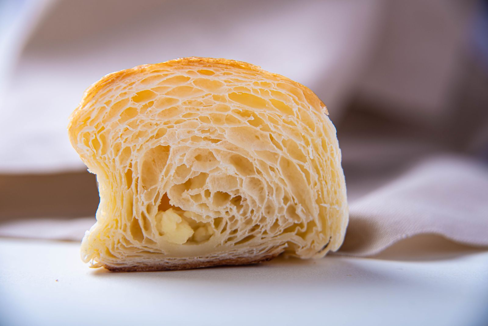Detailed close-up of a freshly baked croissant slice, highlighting its flaky texture and layers.