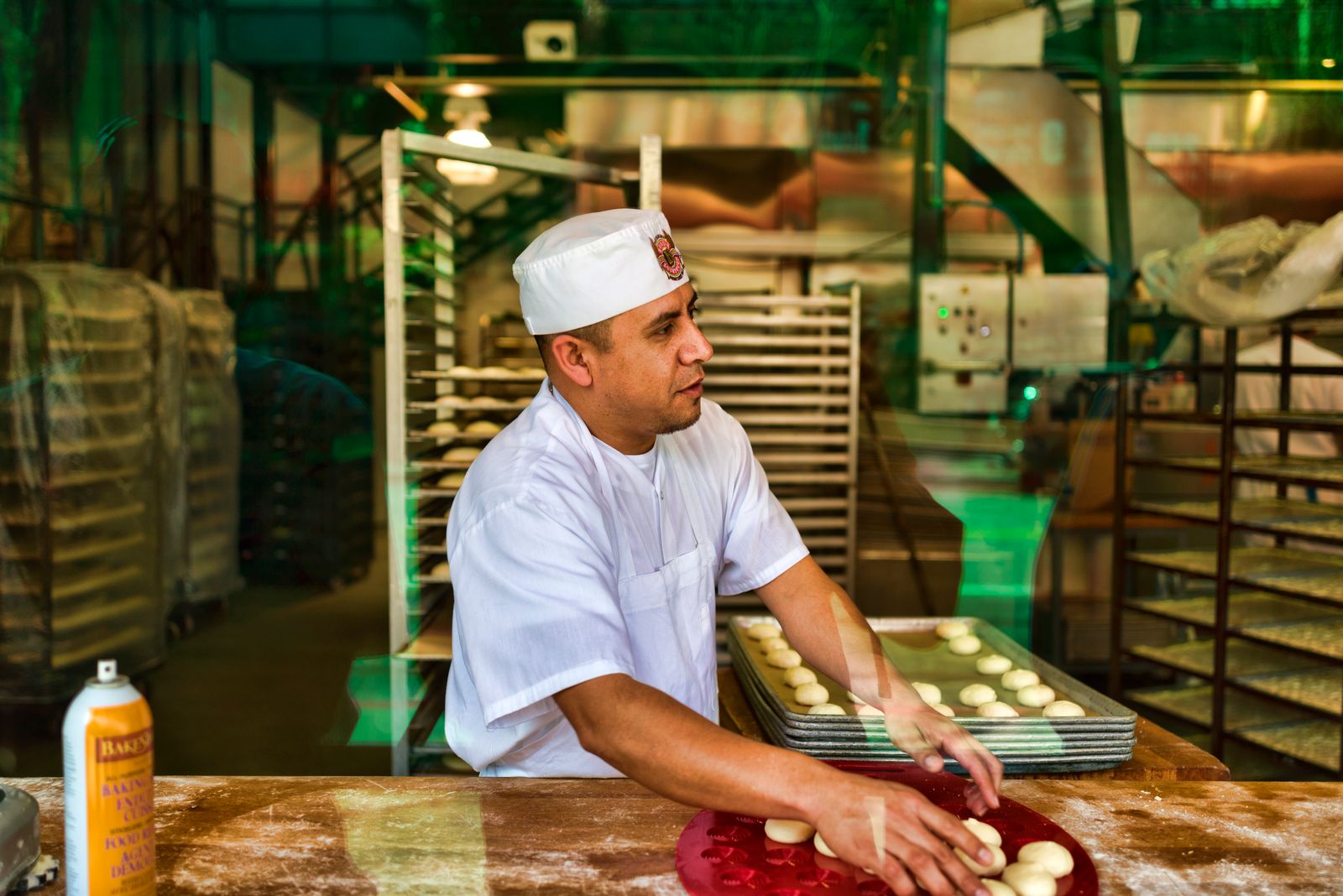 Baker shaping dough on a work table in a bustling San Francisco bakery.