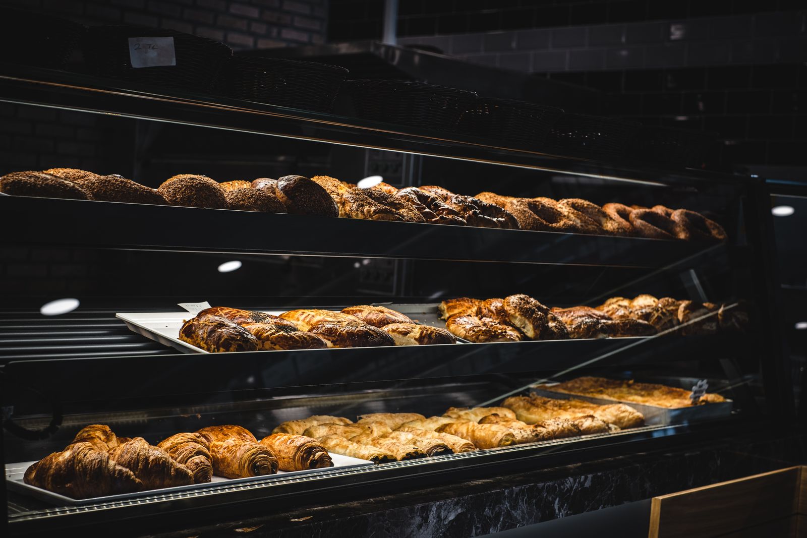 A bakery counter stacked with croissants and morning buns